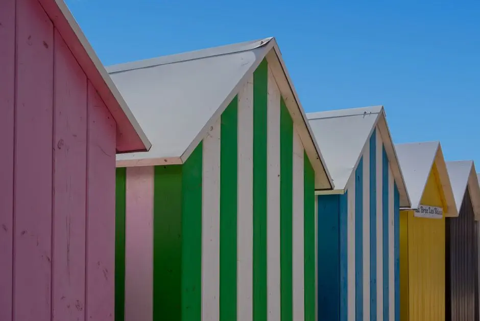 Vibrant striped beach huts under a clear blue sky, showcasing summer vibes.
